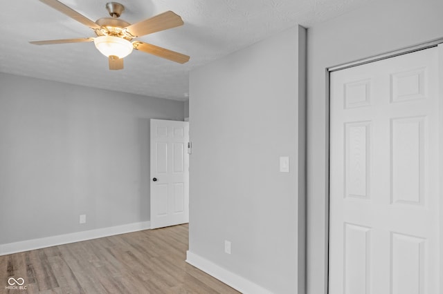 unfurnished bedroom featuring ceiling fan, a textured ceiling, a closet, and light wood-type flooring