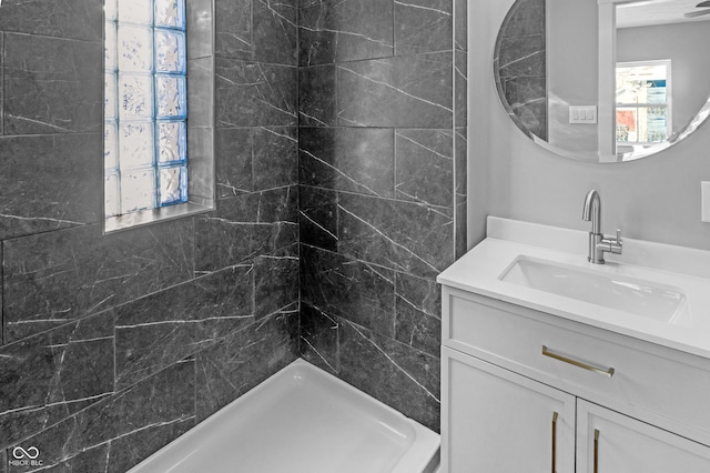 bathroom featuring tiled shower and vanity