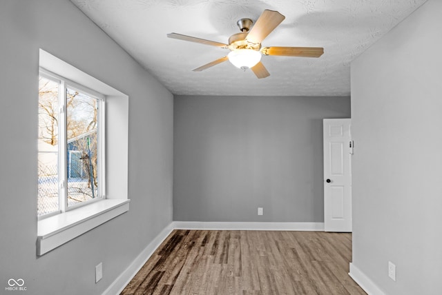 spare room featuring ceiling fan, plenty of natural light, a textured ceiling, and wood-type flooring