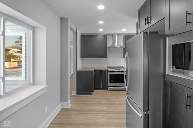 kitchen featuring light hardwood / wood-style floors, stainless steel appliances, wooden counters, and wall chimney exhaust hood