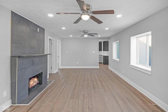 unfurnished living room with a textured ceiling, a fireplace, and wood-type flooring