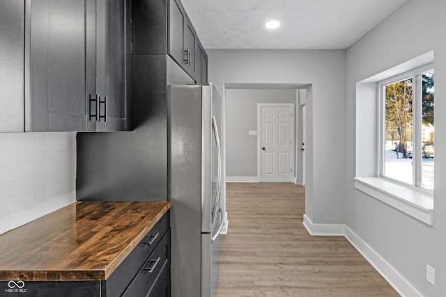 kitchen featuring light wood-type flooring, a textured ceiling, wood counters, and tasteful backsplash