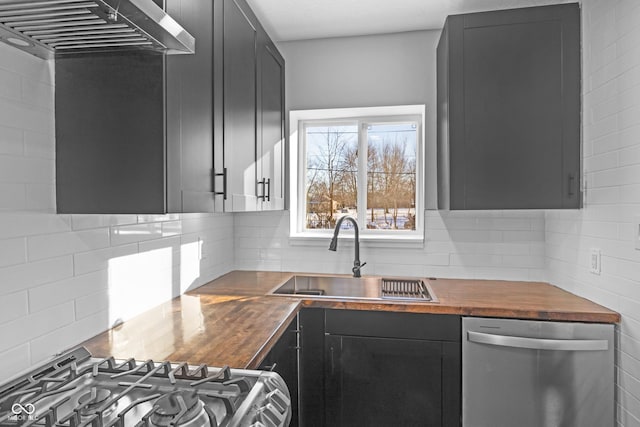 kitchen featuring sink, wall chimney range hood, appliances with stainless steel finishes, and wood counters