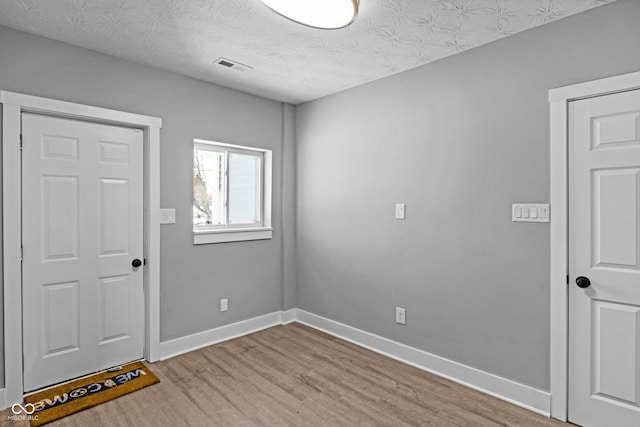 spare room featuring light hardwood / wood-style floors and a textured ceiling