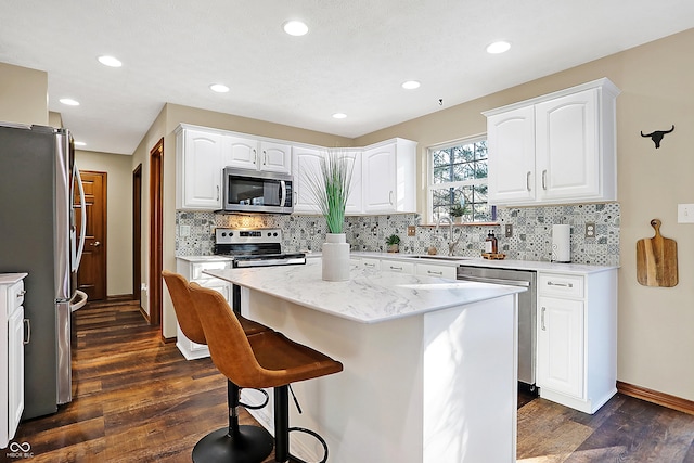 kitchen featuring white cabinetry, a kitchen island, dark wood-type flooring, and appliances with stainless steel finishes