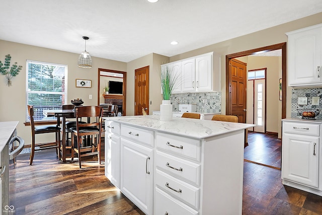 kitchen featuring dark hardwood / wood-style flooring, backsplash, decorative light fixtures, white cabinets, and a kitchen island