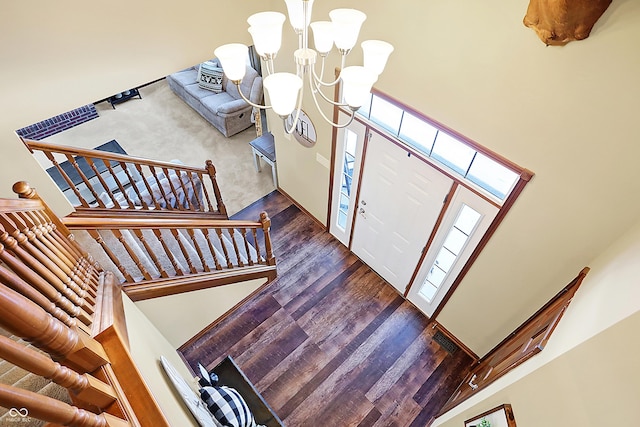 entrance foyer featuring a notable chandelier, a healthy amount of sunlight, a towering ceiling, and dark hardwood / wood-style floors