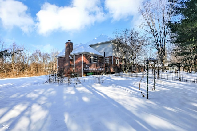 snow covered back of property featuring a wooden deck