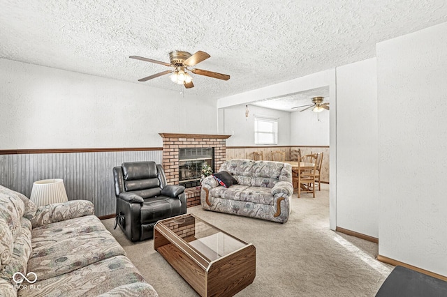 living room with light carpet, a fireplace, ceiling fan, and a textured ceiling