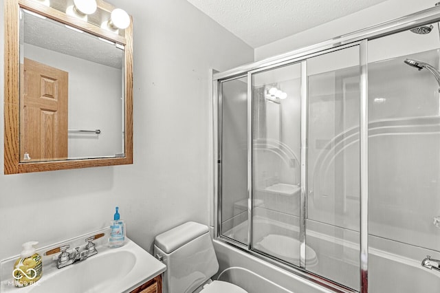 full bathroom with vanity, a textured ceiling, toilet, and bath / shower combo with glass door