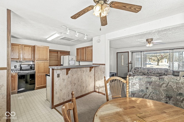 kitchen with kitchen peninsula, a textured ceiling, a breakfast bar, and white fridge