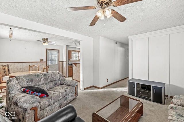 living room with ceiling fan, light colored carpet, and a textured ceiling