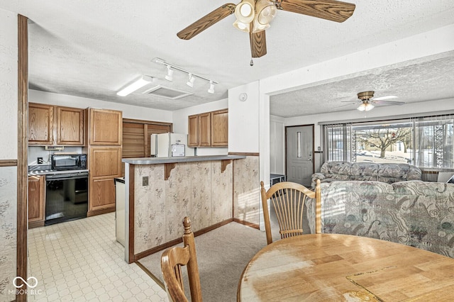 kitchen featuring a kitchen breakfast bar, white fridge, kitchen peninsula, and a textured ceiling