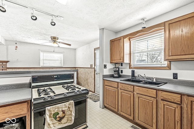 kitchen with gas stove, ceiling fan, sink, and a textured ceiling