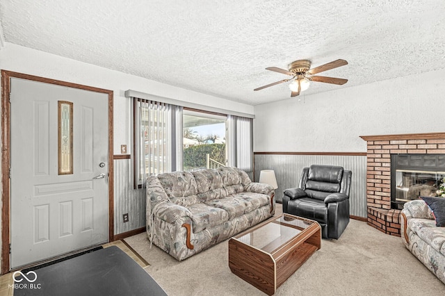 carpeted living room featuring ceiling fan, a fireplace, wood walls, and a textured ceiling