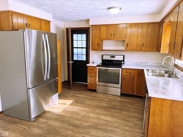 kitchen with wood-type flooring, appliances with stainless steel finishes, and sink