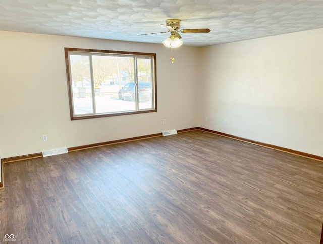 empty room with ceiling fan, dark wood-type flooring, and a textured ceiling