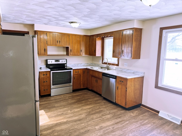 kitchen with a textured ceiling, light hardwood / wood-style floors, sink, and appliances with stainless steel finishes