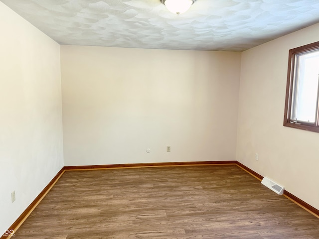 empty room with a textured ceiling and hardwood / wood-style flooring