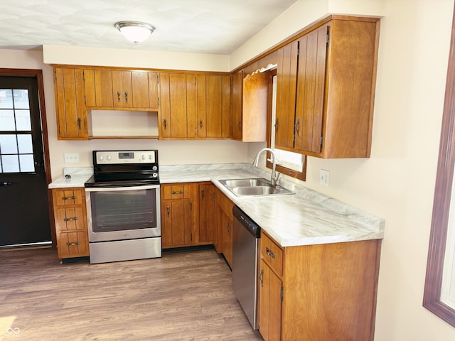 kitchen with a healthy amount of sunlight, sink, light wood-type flooring, and appliances with stainless steel finishes