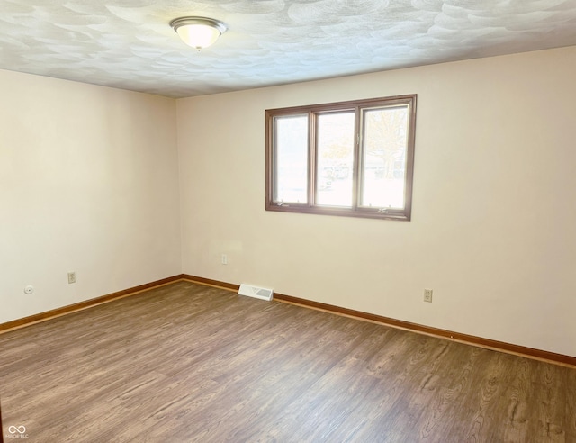 empty room featuring hardwood / wood-style flooring and a textured ceiling