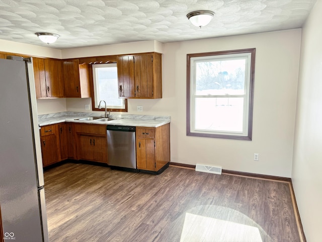 kitchen with wood-type flooring, refrigerator, stainless steel dishwasher, and sink