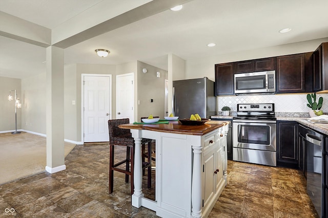 kitchen featuring a kitchen bar, tasteful backsplash, white cabinetry, appliances with stainless steel finishes, and a kitchen island