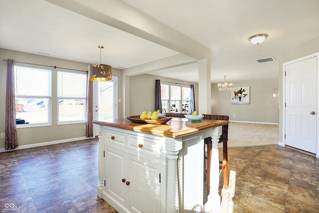 kitchen featuring wooden counters, a chandelier, hanging light fixtures, a kitchen island, and white cabinets