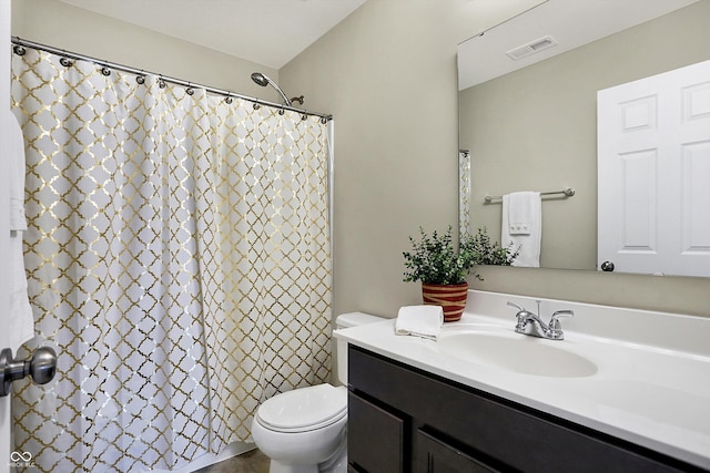 bathroom featuring vanity, walk in shower, and toilet