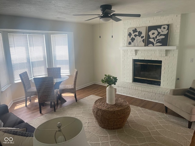 dining area featuring ceiling fan, light hardwood / wood-style floors, a textured ceiling, and a fireplace