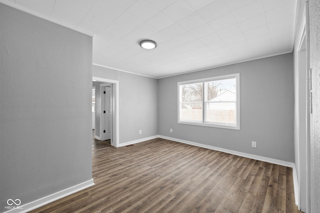 spare room featuring dark hardwood / wood-style floors and crown molding