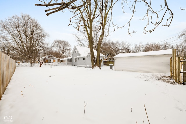 snowy yard featuring an outbuilding and a garage