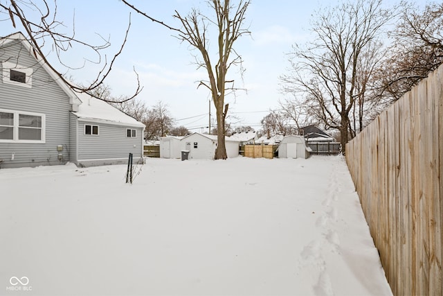 snowy yard featuring a shed