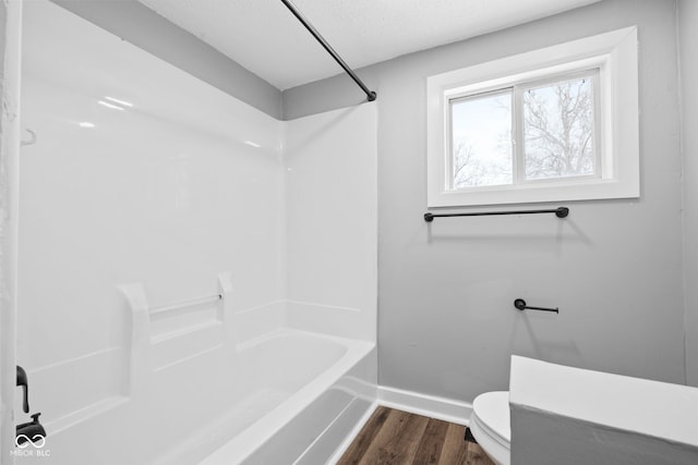 bathroom with wood-type flooring, a textured ceiling, toilet, and  shower combination