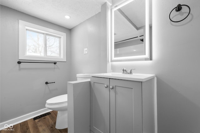 bathroom featuring vanity, hardwood / wood-style floors, a textured ceiling, and toilet