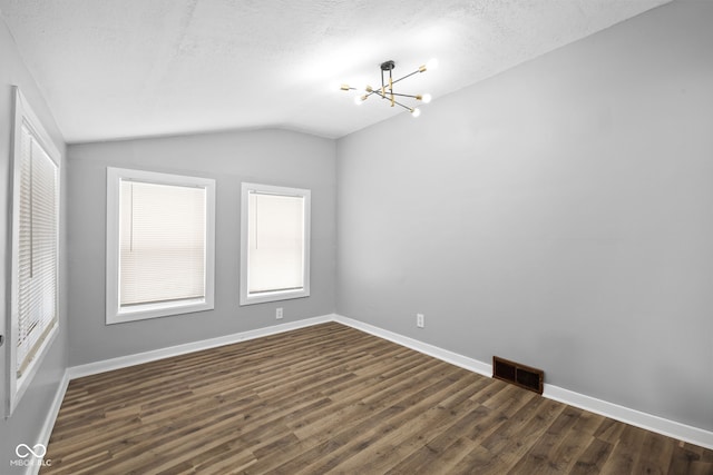 spare room featuring a textured ceiling, dark hardwood / wood-style floors, lofted ceiling, and a notable chandelier