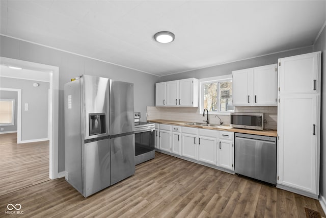 kitchen featuring decorative backsplash, appliances with stainless steel finishes, light wood-type flooring, sink, and white cabinetry