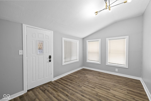 entrance foyer with dark hardwood / wood-style flooring, lofted ceiling, a textured ceiling, and an inviting chandelier