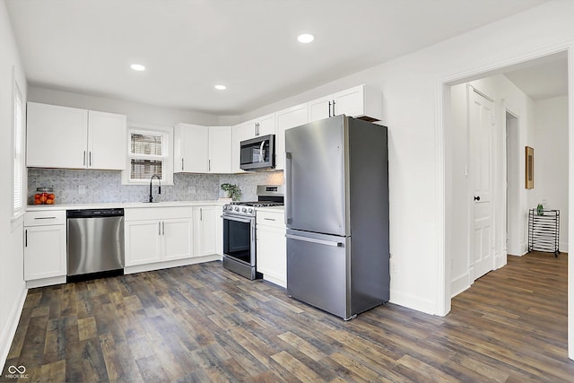 kitchen featuring appliances with stainless steel finishes, tasteful backsplash, white cabinetry, sink, and dark wood-type flooring