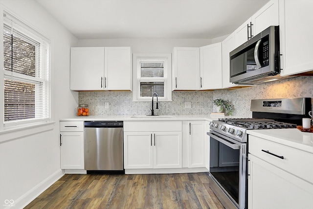 kitchen featuring appliances with stainless steel finishes, white cabinetry, sink, dark hardwood / wood-style flooring, and decorative backsplash