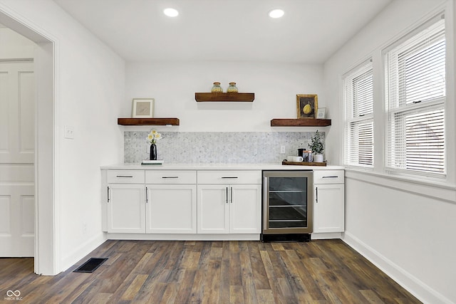 bar with wine cooler, dark wood-type flooring, and white cabinets