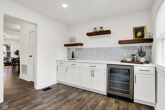 bar with wine cooler, decorative backsplash, dark wood-type flooring, and white cabinets