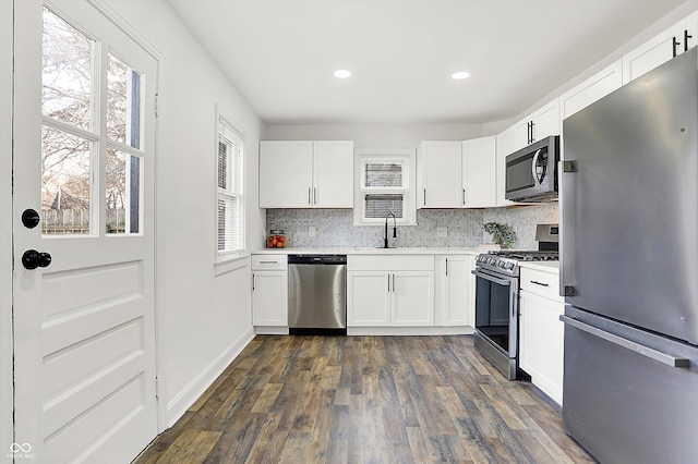 kitchen featuring sink, appliances with stainless steel finishes, dark hardwood / wood-style floors, tasteful backsplash, and white cabinets