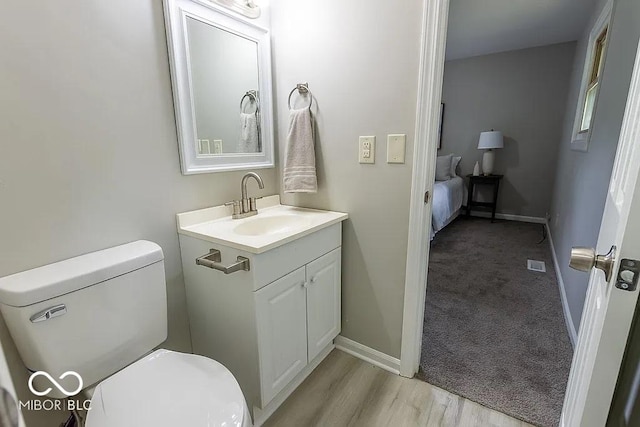 bathroom with hardwood / wood-style floors, vanity, and toilet