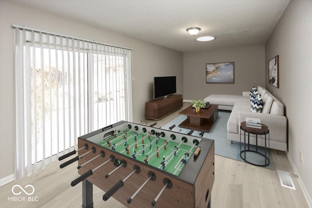 recreation room with light hardwood / wood-style floors and a textured ceiling