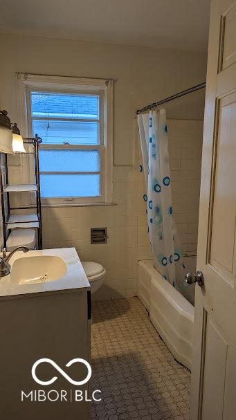 full bathroom with tile patterned flooring, tile walls, toilet, shower / bath combination with curtain, and vanity