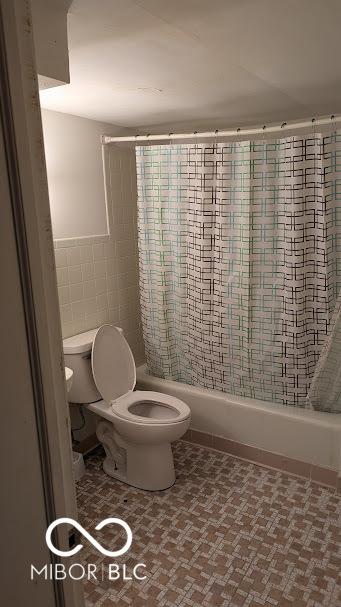 bathroom featuring toilet, tile walls, and shower / tub combo