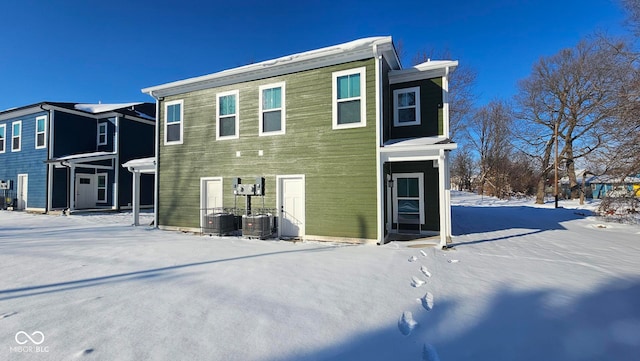 snow covered house featuring cooling unit