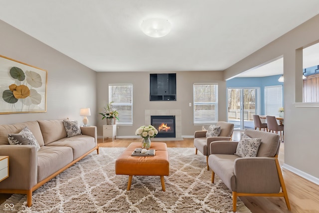 living room featuring a tile fireplace and light wood-type flooring