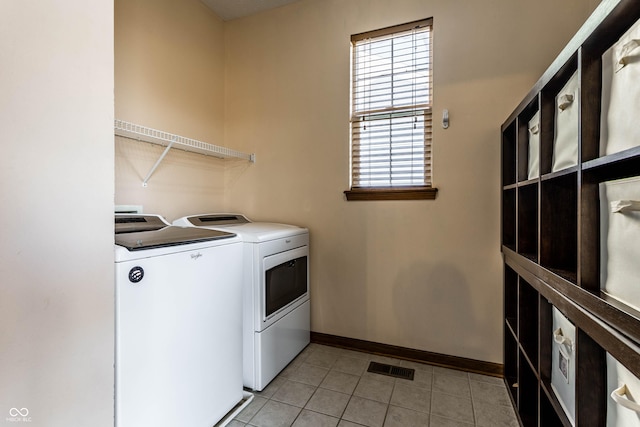 washroom with light tile patterned floors, baseboards, visible vents, laundry area, and washing machine and dryer